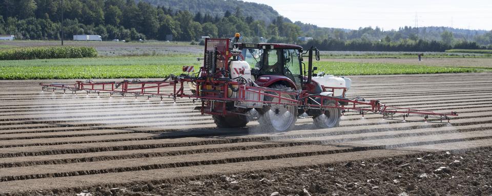 Un tracteur épand un herbicide. [Keystone - Christian Beutler]