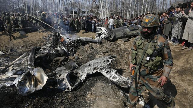 Un soldat indien passe vers l'épave d'un avion dans le Cachemire. [Keystone - AP/Mukhtar Khan]