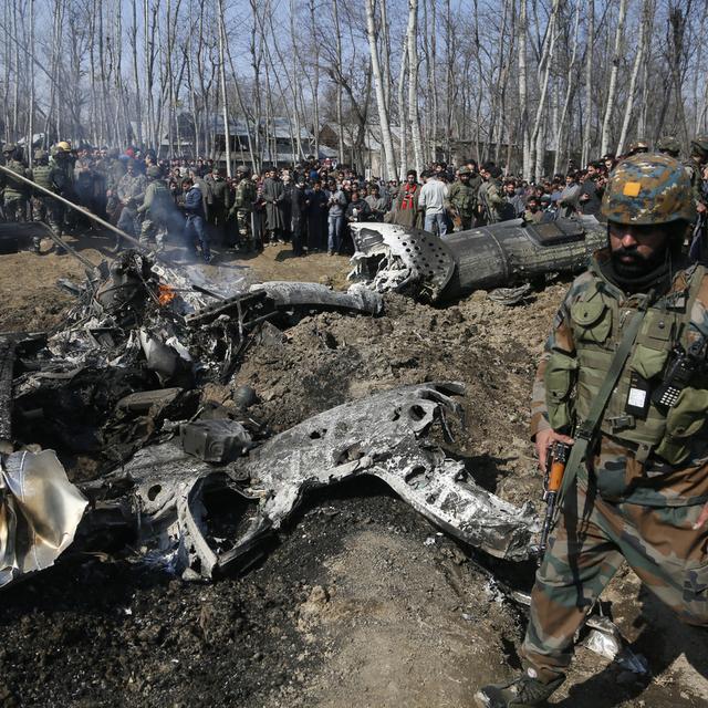 Un soldat indien passe vers l'épave d'un avion dans le Cachemire. [Keystone - AP/Mukhtar Khan]