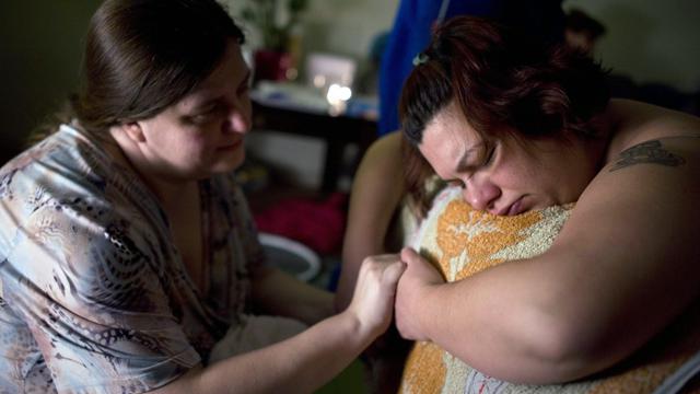 Une Doula tenant les mains d'une femme hongroise ayant choisi une naissance à la maison [EPA/Keystone - Bea Kallos]