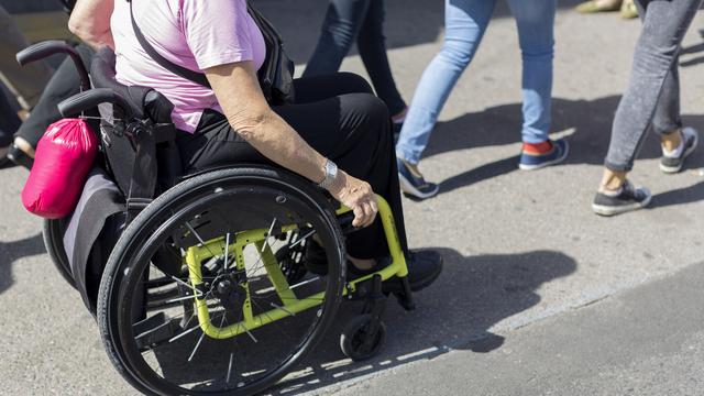 Une personnes circule dans la rue en chaise roulante. (image d'illustration) [Keystone - Gaetan Bally]