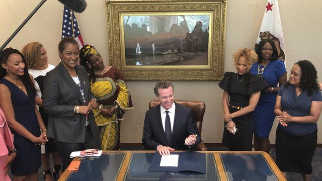 Le gouverneur de Californie Gavin Newsom signe la loi contre "la discrimination raciale fondée sur les cheveux" sous les yeux de son initiatrice, la sénatrice démocrate de Los Angeles Holly Mitchell (3e depuis la gauche). [Keystone - AP Photo/Kathleen Ronayne]