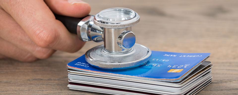 Un stéthoscope ausculte une pile de cartes de crédit. [Depositphotos - AndreyPopov]