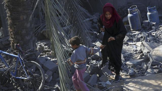 Des Palestiniens se déplacent entre les décombres d'une maison après les bombardements de l'armée israélienne, le 14 novembre 2019. [Keystone - Adel Hana]