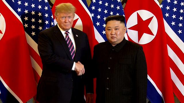 Kim Jong-Un et Donald Trump ont eu une première poignée de mains devant une rangée de drapeaux. [AP/Keystone - Host Broadcast]