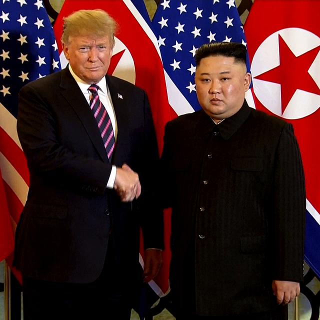 Kim Jong-Un et Donald Trump ont eu une première poignée de mains devant une rangée de drapeaux. [AP/Keystone - Host Broadcast]