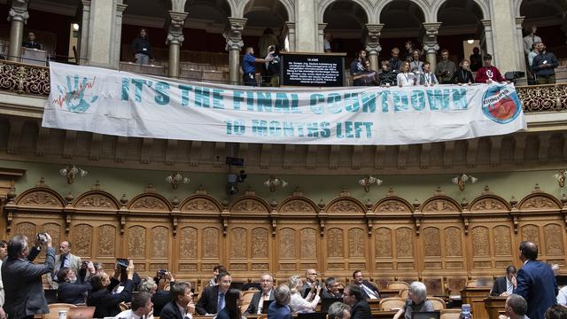 La banderole déroulée par les manifestants pour le climat, jeudi au Conseil national. [Keystone - Peter Schneider]