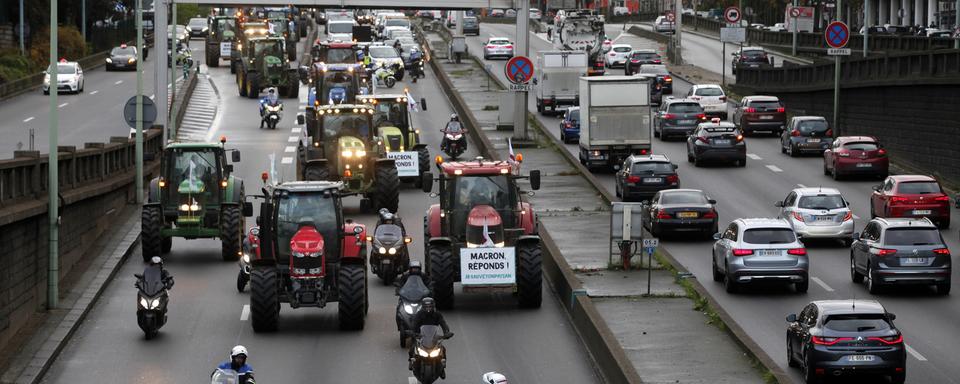 Les agriculteurs en tracteur à Paris manifestent leur colère. [AP Photo/Keystone - Thibault Camus]