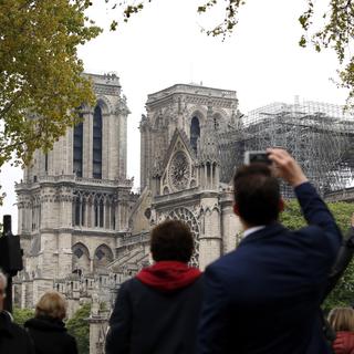 Des passants photographient la cathédrale sinistrée. [AP Photo - Christophe Ena]