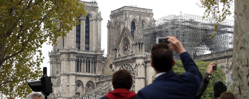 Des passants photographient la cathédrale sinistrée. [AP Photo - Christophe Ena]