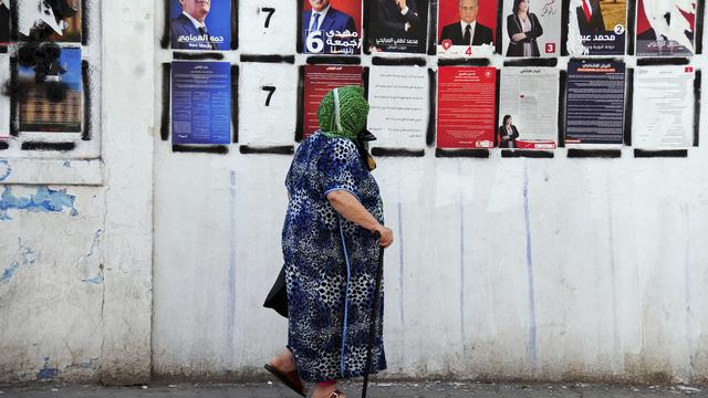 Une femme passe devant les affiches des nombreux candidats à la présidentielle tunisienne, le 14 septembre à Tunis. [AP Photo - Hassene Dridi]