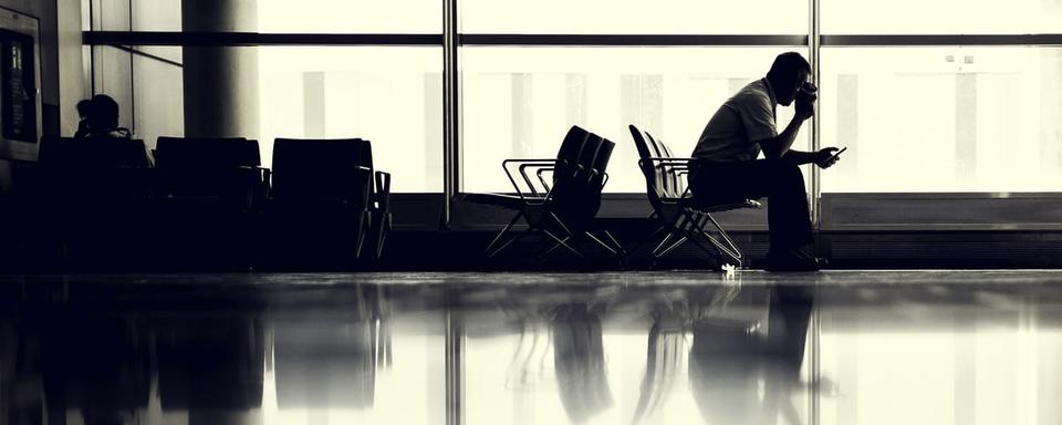 Un homme attend son avion dans un aéroport. [Unsplash - JESHOOTS.COM]