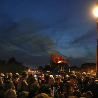 La foule observe Notre-Dame en flammes. [Keystone - EPA/Ian Langsdon]