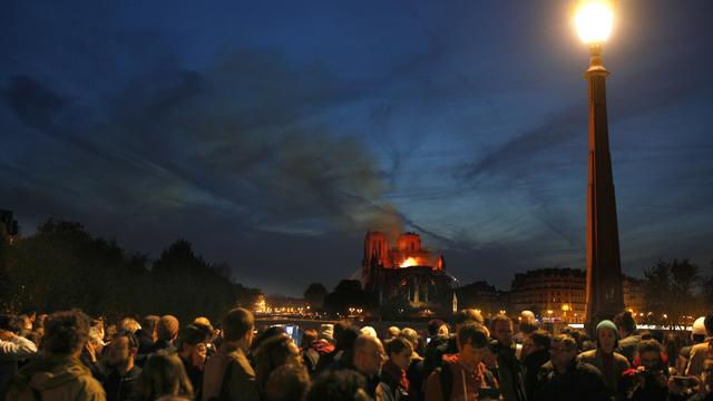 La foule observe Notre-Dame en flammes. [Keystone - EPA/Ian Langsdon]