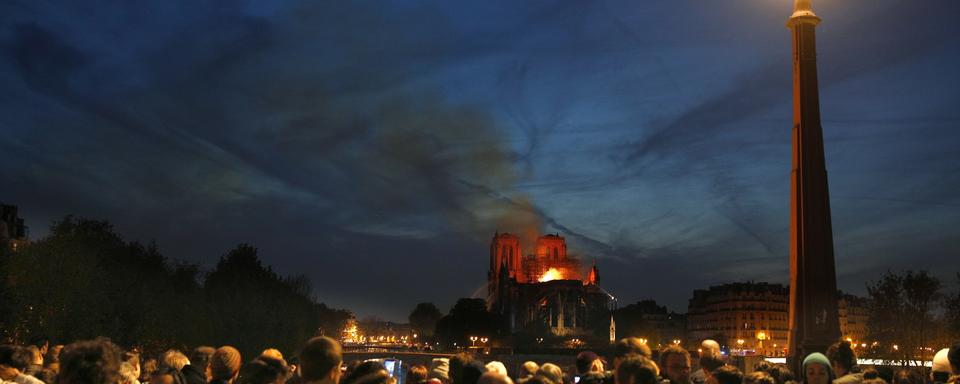 La foule observe Notre-Dame en flammes. [Keystone - EPA/Ian Langsdon]