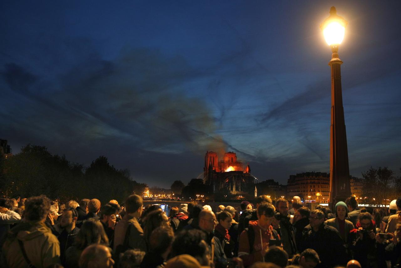 La foule observe Notre-Dame en flammes. [Keystone - EPA/Ian Langsdon]