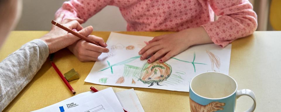 Une mère avec sa fille dessinant sur une table de cuisine (image d'illustration). [Keystone - Christof Schuerpf]