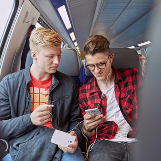 Des personnes utilisant leur téléphone portable dans un train. [Keystone - Christof Schuerpf]