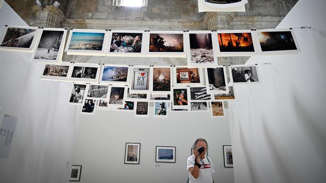 Un homme prend en photo l'exposition sur les 50 ans des Rencontres photographiques d'Arles. [AFP - Gérard Julien]