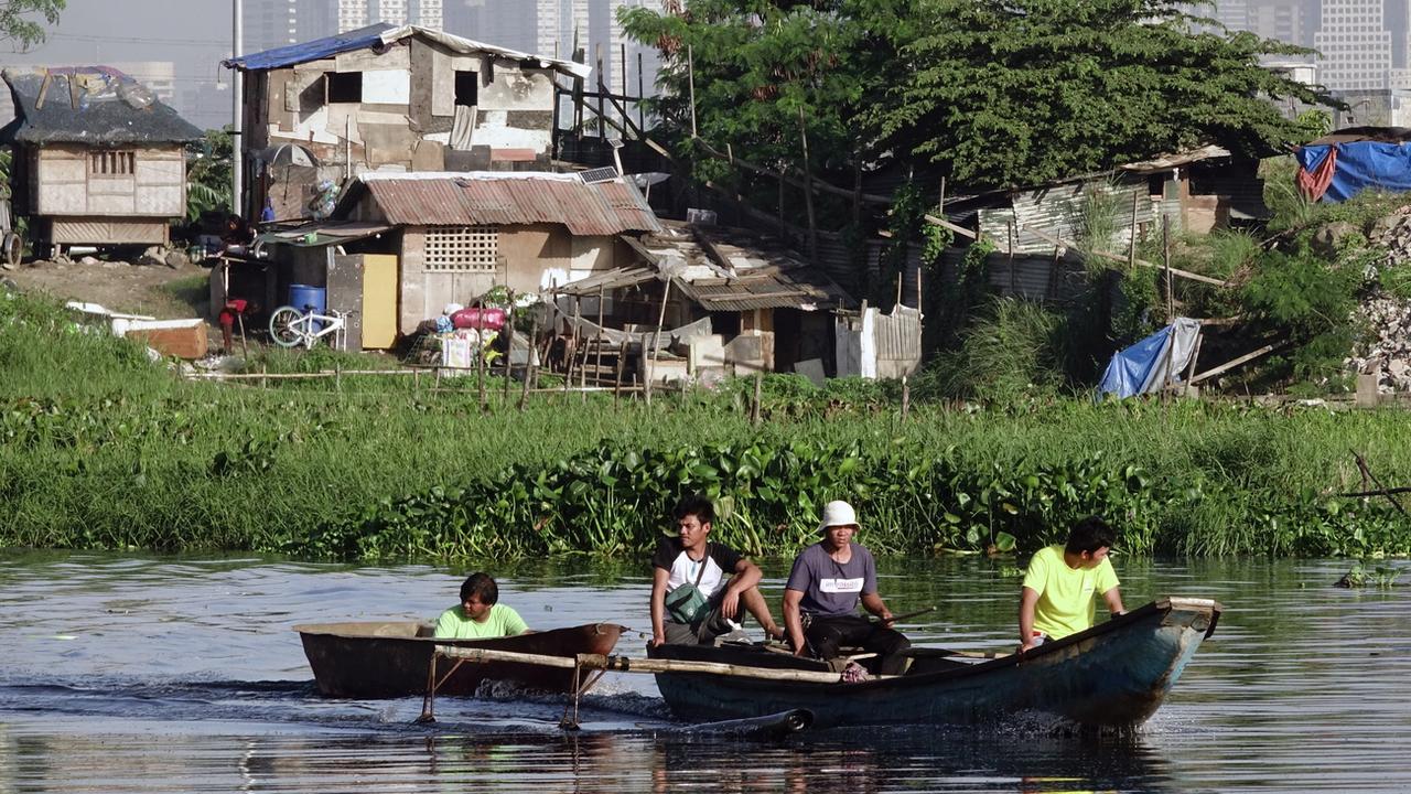 Des Philippins traversent en barque des champs inondés près de la ville de Taguig, aux Philippines, le 4 janvier 2019. [Keystone - Francis R. Malasig]