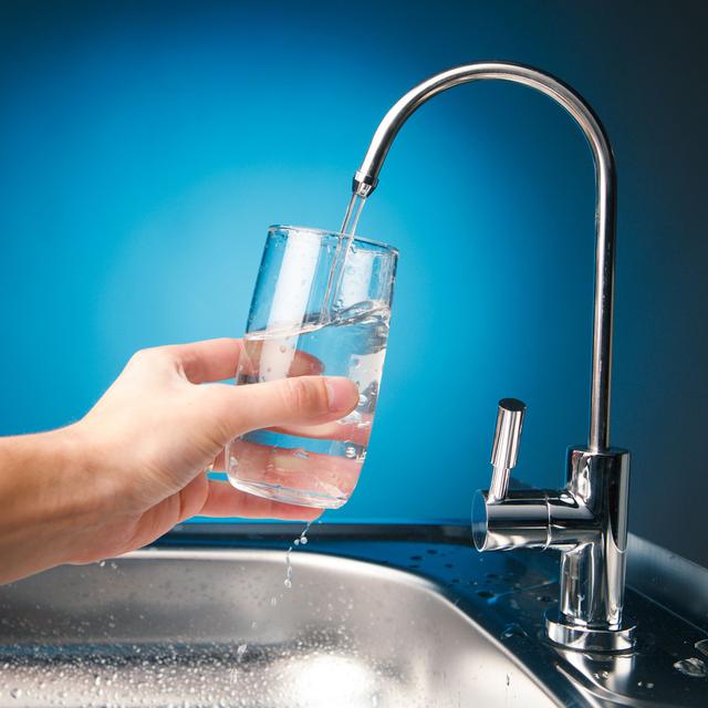 Une personne se sert un verre d'eau au robinet. [Depositphotos - nikkytok]