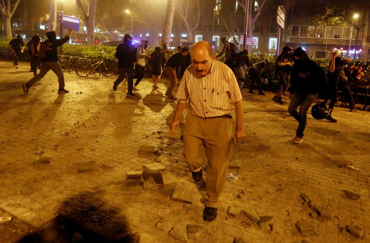 Un homme enlève des pavés des mains des manifestants, durant la grève générale à Barcelone, le 18 octobre 2019. [Reuters - Jon Nazca]