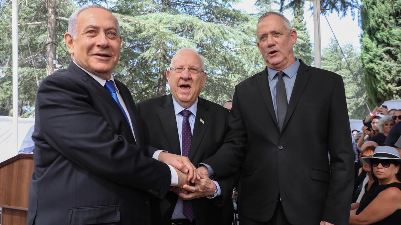 Benjamin Netanyahu, Reuven Rivlin et Benny Gantz (de gauche à droite) se sont serré la main jeudi lors d'une cérémonie marquant jeudi le troisième anniversaire de la mort de l'ancien Premier ministre Shimon Peres. [Keystone/EPA - Abir Sultan]