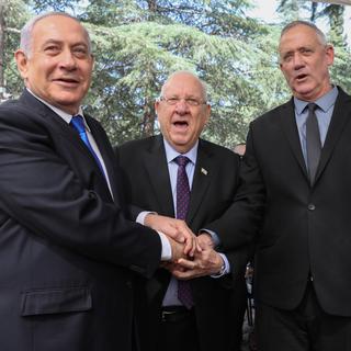 Benjamin Netanyahu, Reuven Rivlin et Benny Gantz (de gauche à droite) se sont serré la main jeudi lors d'une cérémonie marquant jeudi le troisième anniversaire de la mort de l'ancien Premier ministre Shimon Peres. [Keystone/EPA - Abir Sultan]