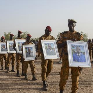 Le 20 décembre 2016 à Ouagadougou, des militaires burkinabè défilent avec les portraits de soldats tués lors d'une attaque du groupe islamique Ansaroul Islam à Nassoumbou. [AFP - Ahmed Ouoba]