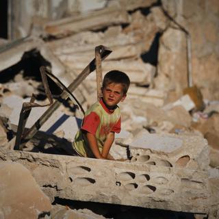 Un enfant syrien dans les ruines de la ville de Taftanaz, dans la province d'Idleb. [Keystone - AP]