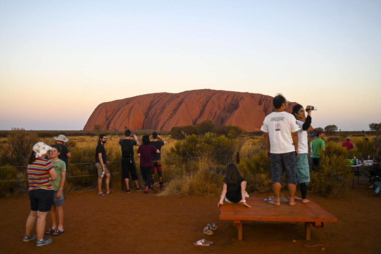 Des touristes devant le rocher d'Uluru. [Keystone - Lukas Coch/AAP Image via AP]