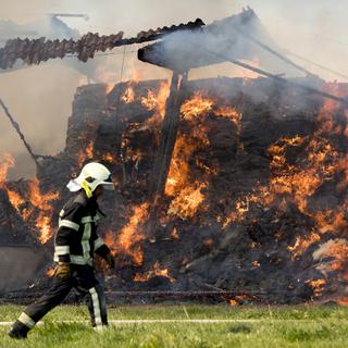 Des pompiers travaillent à éteindre l'incendie d'un rural d'une ferme le 21 septembre 2019 à Vuarrens dans le Gros-de-Vaud. [Keystone - Laurent Gillieron]