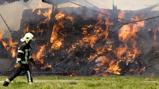 Des pompiers travaillent à éteindre l'incendie d'un rural d'une ferme le 21 septembre 2019 à Vuarrens dans le Gros-de-Vaud. [Keystone - Laurent Gillieron]