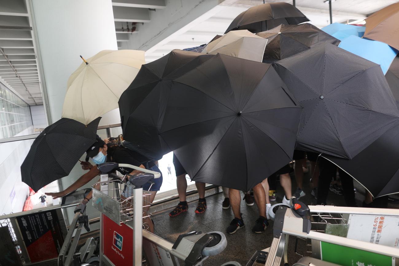 Les protestataires se planquent derrière des parapluies pour éviter les caméras de surveillance. [EPA/Keystone - Jérôme Favre]