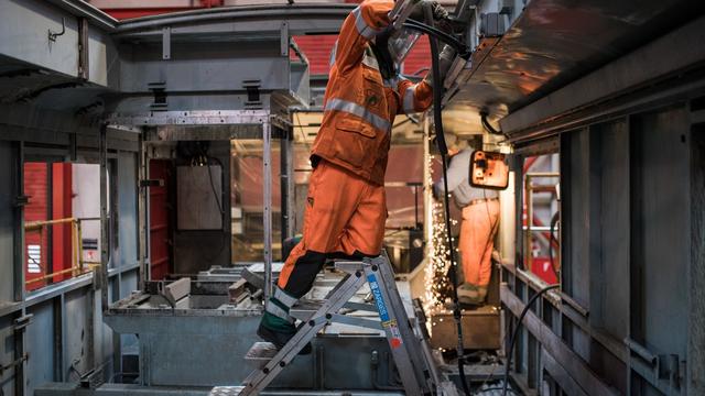 Des ouvriers des ateliers CFF de Bellinzone rénovent une locomotive. [Keystone/Ti-Press - Gabriele Putzu]