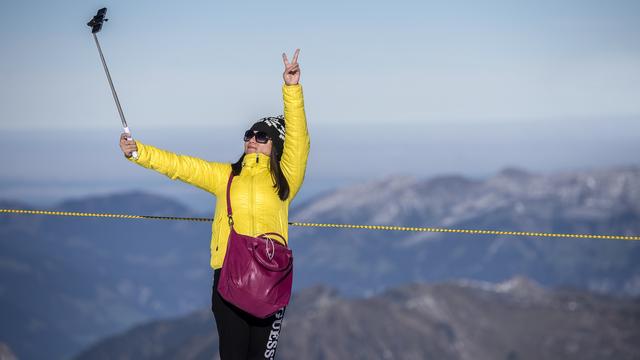 Une touriste chinoise se prenant en photo au sommet du Titlis, dans le canton d'Obwald. [Keystone - Urs Flueeler]