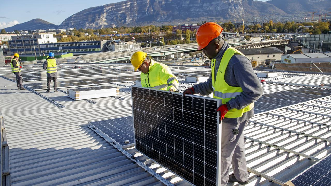 Des ouvriers posent des panneaux solaires sur le toit du stade de Genève, le 12 novembre 2019. [Keystone - Salvatore Di Nolfi]