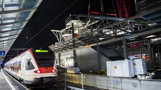 Des ouvriers travaillent sur le premier élément de la passerelle "Rayon Vert" au-dessus des voies de la gare CFF de Renens, la nuit du vendredi 29 au samedi 30 novembre 2019. [Keystone - Jean-Christophe Bott]