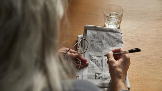 Une femme âgée faisant un jeu de chiffres. [Keystone - Christof Schuerpf]