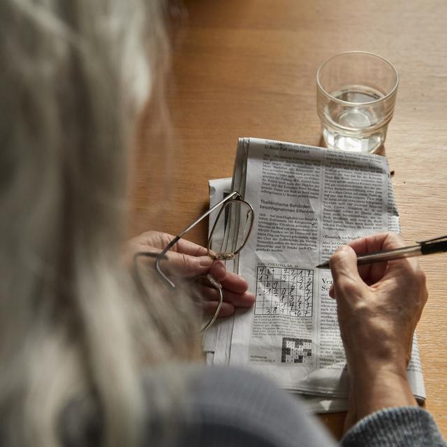 Une femme âgée faisant un jeu de chiffres. [Keystone - Christof Schuerpf]