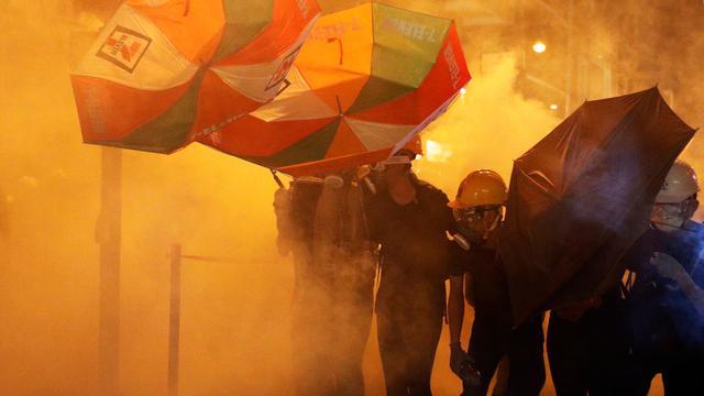 Des militants tentent de ce protéger des gaz lacrymogènes avec leurs parapluies. [Reuters - Edgar Su]