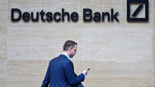 Un homme passe devant le logo de Deutsche Bank. [EPA-Keystone - Facundo Arrizabalaga]