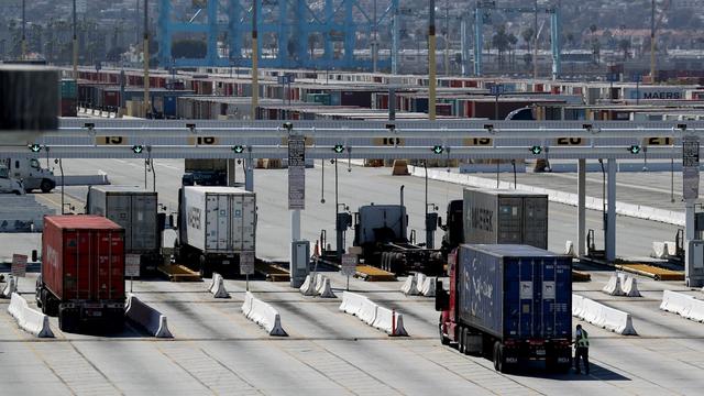 Des camions sortent des containers du port de Los Angeles. [Keystone - Andrew Gombert/EPA]