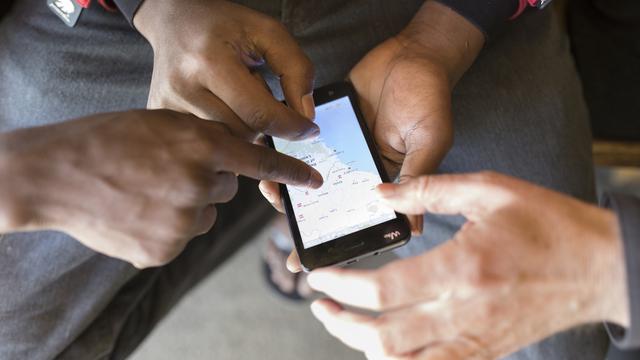 Un demandeur d'asile montre d'où il vient sur son téléphone portable. [Keystone - Gaetan Bailly]