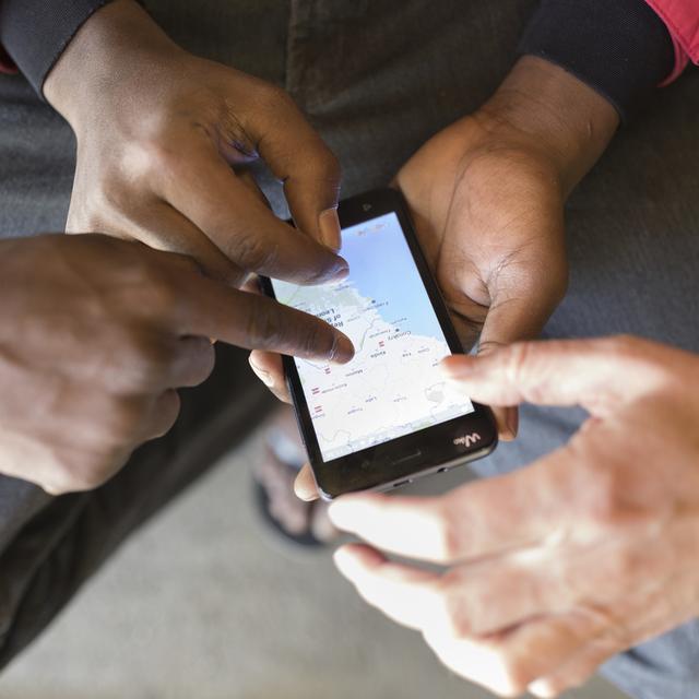 Un demandeur d'asile montre d'où il vient sur son téléphone portable. [Keystone - Gaetan Bailly]