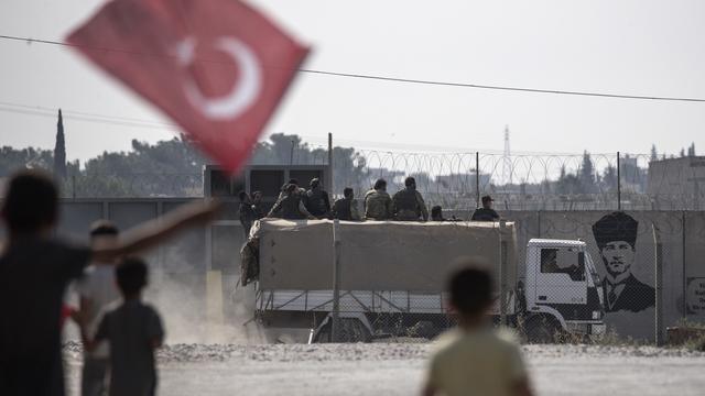 Des enfants tiennent des drapeaux turcs lors d'un déplacement de l'armée vers les zones kurdes de Syrie [EPA/Keystone - Erdem Sahin]