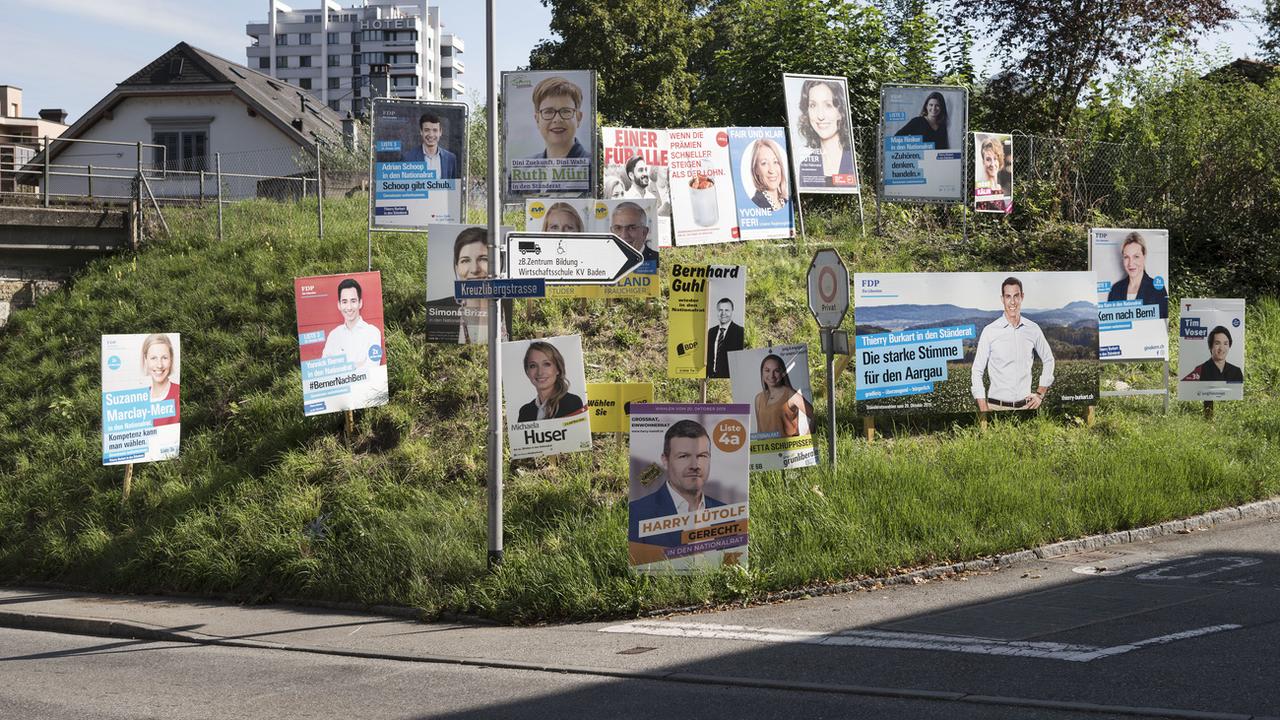 Les affiches de campagne de différent.e.s candidat.e.s aux élections fédérales photographiées mi-septembre à Baden (AG). [Keystone - Christian Beutler]