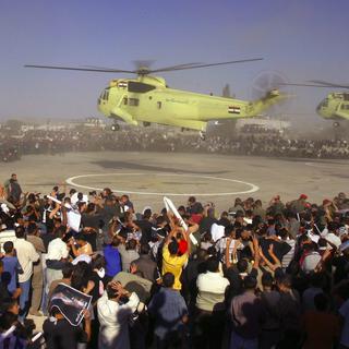 Deux hélicoptères de l'armée égyptienne rapatrient la dépouille de Yasser Arafat à Ramallah en Cisjordanie devant la foule palestinienne venue assister à ses funérailles, le 12 novembre 2004. [EPA / Keystone - Jim Hollander]