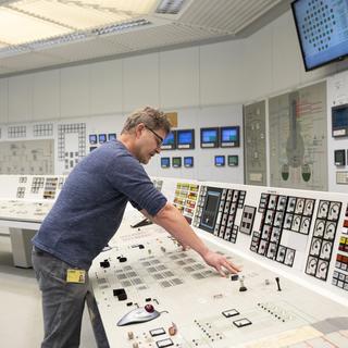Un technicien pousse le bouton qui permet d'éteindre le réacteur de Mühleberg lors de l'arrêt officiel de la centrale nucléaire. [Keystone - Peter Klaunzer]