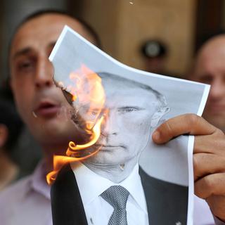Un protestataire brûle une image du président russe lors d'une manifestation à Tbilissi le 20.06.2019. [Reuters - Irakli Gedenidze]